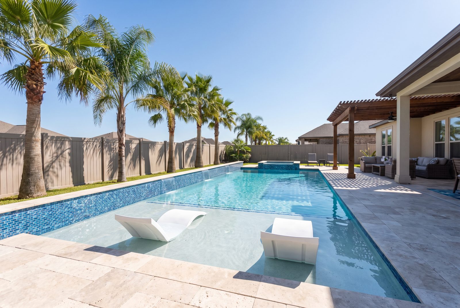 Modern custom pool with a tanning ledge sun shelf and travertine deck at a McAllen home